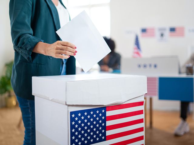 a ballet box with an American Flag with someone putting in a vote